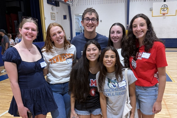 Seven STM Class of 2022 graduates pose for photo in the gym at their reunion