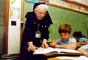 A historic photo of a nun teaching a student in a Saint Thomas More Catholic School classroom